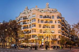 un grand bâtiment jaune dans une rue de la ville dans l'établissement Sweet Inn - La Pedrera - Paseo de Gracia, à Barcelone