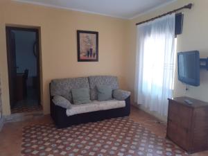 een woonkamer met een bank en een tv bij Apartamentos Isabel in Maro