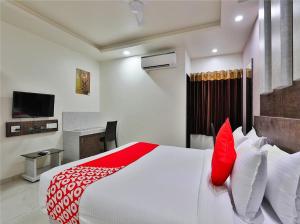 1 dormitorio con 1 cama blanca grande con almohadas rojas en The Sky Comfort Hotel Parth Inn, en Dwarka