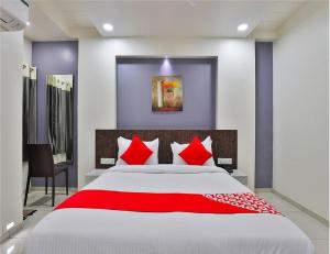 1 dormitorio con 1 cama grande con almohadas rojas en The Sky Comfort Hotel Parth Inn, en Dwarka