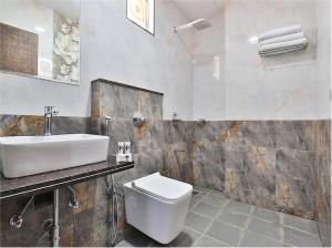 y baño con aseo blanco y lavamanos. en The Sky Comfort Hotel Parth Inn, en Dwarka