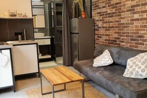 a living room with a couch and a brick wall at Studio BARACHOIS, 26 m² rez de jardin in Saint-Denis