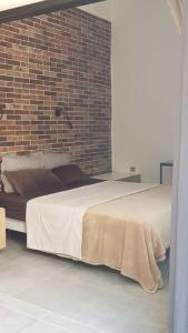 a bedroom with a large bed with a brick wall at Studio BARACHOIS, 26 m² rez de jardin in Saint-Denis