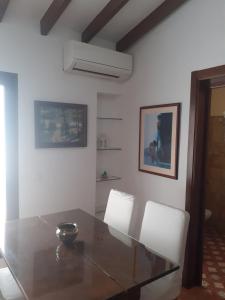 ein Esszimmer mit einem Glastisch und zwei weißen Stühlen in der Unterkunft Apartamentos Isabel in Maro