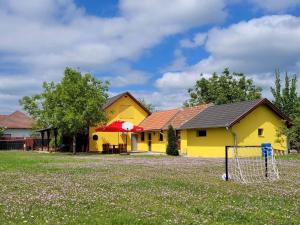 a yellow building with a goal in front of it at Erika Vendégház in Tiszasas