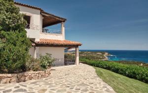 une maison avec une passerelle à côté de l'océan dans l'établissement Vistamare Grande Pevero, à Porto Cervo