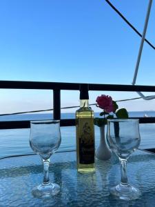 una bottiglia di vino seduta su un tavolo con due bicchieri da vino di Porto Haraki Studios a Haraki