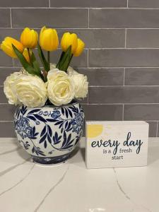 um vaso azul e branco com flores amarelas e um sinal em Travel, Work, Play- alone, family, friends em Mount Prospect