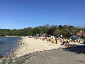 ein Strand mit Stühlen und Menschen laufen auf dem Sand in der Unterkunft Ferienapartment Hartung in Heikendorf