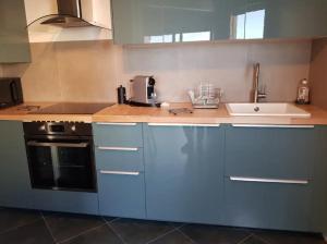 a kitchen with blue cabinets and a sink at Splendide T2 face à la mer, terrasse, wifi in Hendaye +3 photos