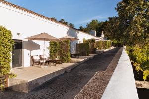 un patio con tavoli e ombrelloni accanto a un edificio di Imani Country House a Évora