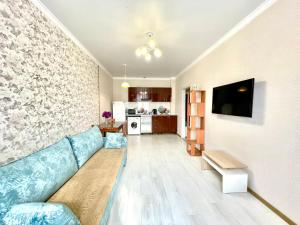 a living room with a blue couch and a kitchen at апартаменты с видом на город in Pavlodar