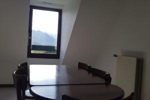 a table and chairs in a room with a window at Grand appartement 4/5 personnes in Bartrés