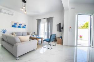 ein weißes Wohnzimmer mit einem Sofa und einem Stuhl in der Unterkunft Fileo Family and Friends Living in Archangelos