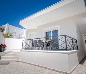 Cette maison blanche dispose d'un balcon avec deux chaises. dans l'établissement Fileo Family and Friends Living, à Archangelos