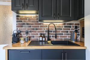 a kitchen with a sink and a brick wall at Appartement T2 - Vue imprenable sur la cathédrale in Quimper