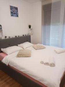 - un grand lit blanc avec 2 paires de chaussons dans l'établissement Gajeva Rooms - Stockholm apartment SELF CHECK-IN, à Virovitica