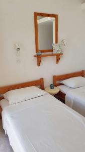 two beds in a room with a mirror on the wall at Porto Haraki Studios in Haraki