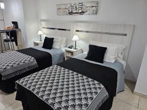 a hotel room with two beds with black and white sheets at Diseño y confort Monoambiente a pasos del Río! in Santa Fe
