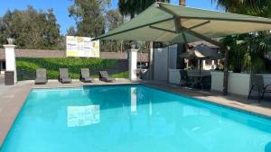 ein großer blauer Pool mit Stühlen und einem Sonnenschirm in der Unterkunft Hotel Siesta Real in Mexicali
