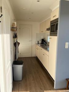 a kitchen with white cabinets and a trash can at Chalet in Nistelrode