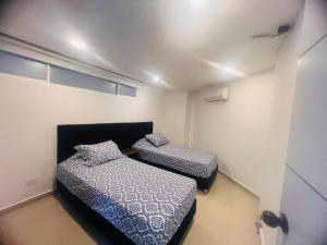 two beds in a small room with a room with a door at Apartamento cerca al mar, terraza con vista 360 in Santa Marta