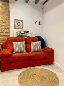 a orange couch in a living room with a rug at Don Quijote in Toledo