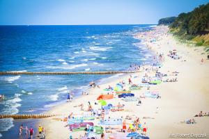 a crowd of people on a beach near the ocean at Domki Letniskowe Blue Sky 1 in Rewal