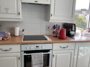 a kitchen with white cabinets and a stove top oven at Riverview Apartment in Buncrana
