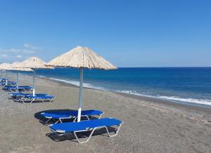 una fila de sillas y sombrillas azules en una playa en Long Beach Resort en Ierápetra