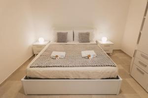 ein weißes Schlafzimmer mit einem großen Bett mit zwei Nachttischen in der Unterkunft Shangri-La Polignano a Mare in Polignano a Mare