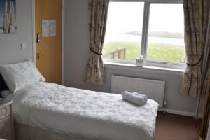 a small bedroom with a bed and a window at Braeswick B&B in Sanday