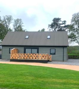a large gray cabin with a wooden deck at Birchwood View in Aboyne