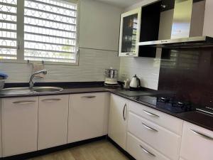 une cuisine avec des armoires blanches et un évier dans l'établissement Villa Liliana, à Sainte-Rose 2 autres photos
