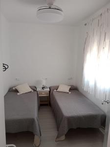 two twin beds in a room with a window at Siorica Beach in Matalascañas