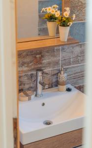 a bathroom sink with two flowers on a shelf at Houses at Chrisopigi Sifnos in Chrisopigi
