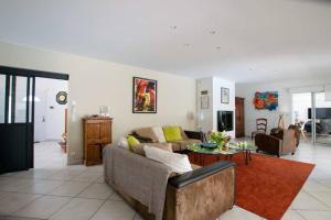 ein Wohnzimmer mit Sofa und Tisch in der Unterkunft Villa Hibiscus à 10 min de l'océan in Saubion