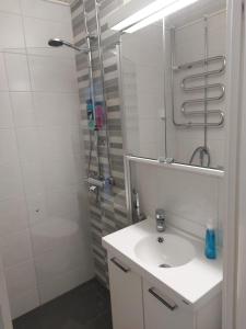 a white bathroom with a sink and a shower at Kiertokatu apartment in Pori