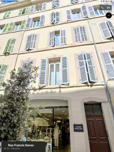 - un grand bâtiment blanc avec des fenêtres blanches à volets dans l'établissement Appartement Vieux-Port de Marseille - Opéra, à Marseille