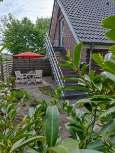 un patio con una mesa y una sombrilla roja en Ferienwohnung Adriane en Nordhorn