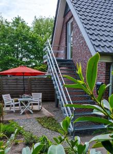 un patio con mesa, sombrilla y escaleras en Ferienwohnung Adriane en Nordhorn