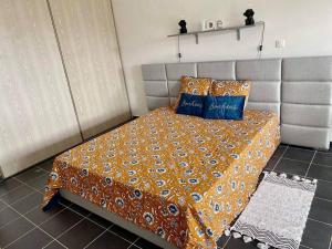 um quarto com uma cama com um cobertor laranja e almofadas azuis em Studio cosy - Situé au Tampon em Le Tampon