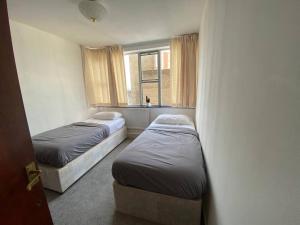 two beds in a room with a window at Sentinel 2 Bed Apartment in NW London in London