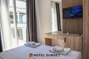 um quarto de hotel ao pôr-do-sol com uma cama e uma televisão em Hotel SUNSET Shengjin em Shëngjin