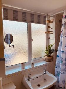 a bathroom with a sink and a window at Cosy Cottage, dog friendly with wood burner in Briston
