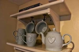 a shelf with cups and a tea pot on it at Cosy Cottage, dog friendly with wood burner in Briston