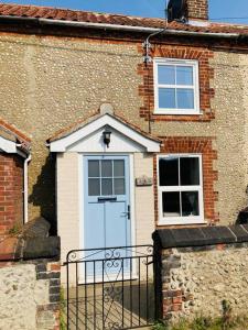 a brick house with a blue door and windows at Cosy Cottage, dog friendly with wood burner in Briston