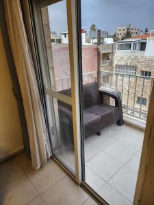 Cette chambre dispose d'un balcon avec une fenêtre et une chaise. dans l'établissement Rana's apartment, à Amman