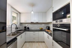 a kitchen with white cabinets and black appliances at Porto Gaios House in Gaios +3 photos