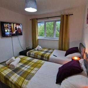 two beds in a room with a tv and window at Pet Friendly 3 Bedroom Apartment in Manchester by Sublime Stays in Manchester